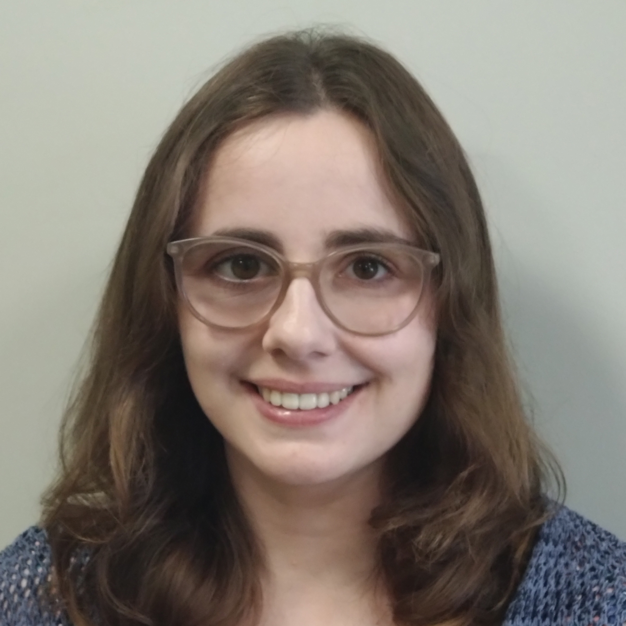 a head and shoulders picture of a young lady with long brown hair wearing glasses