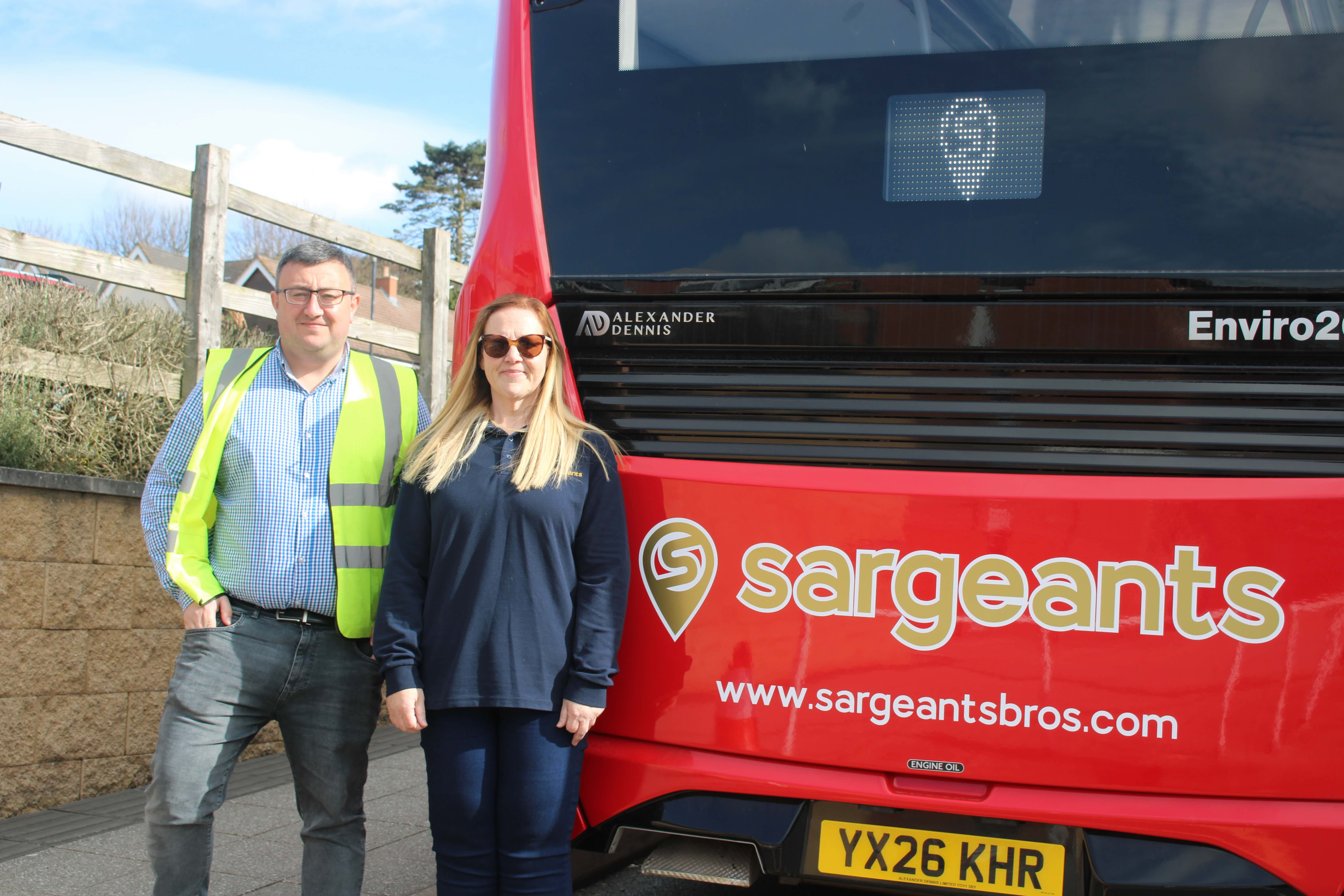 Ashley and Nicola stand at the back of the bus with 'Sargeants' written across it