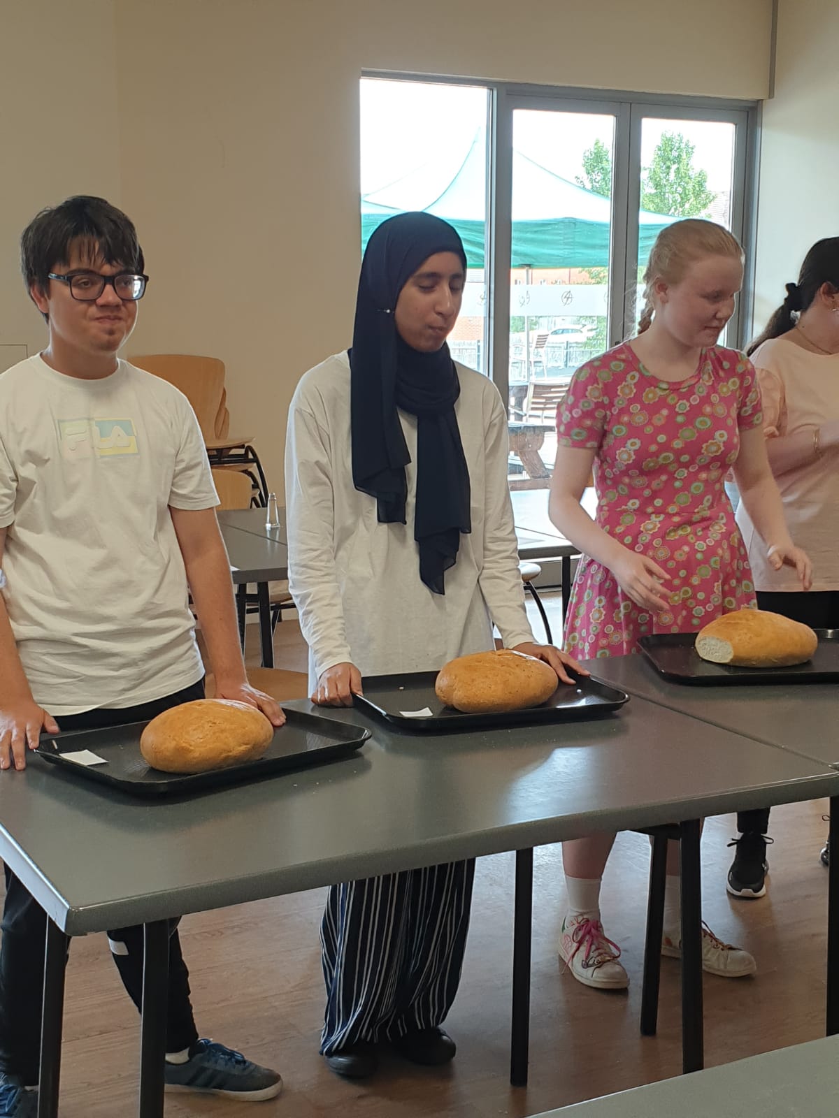 a group of 4 people lined up with their loaves on a table in front of them