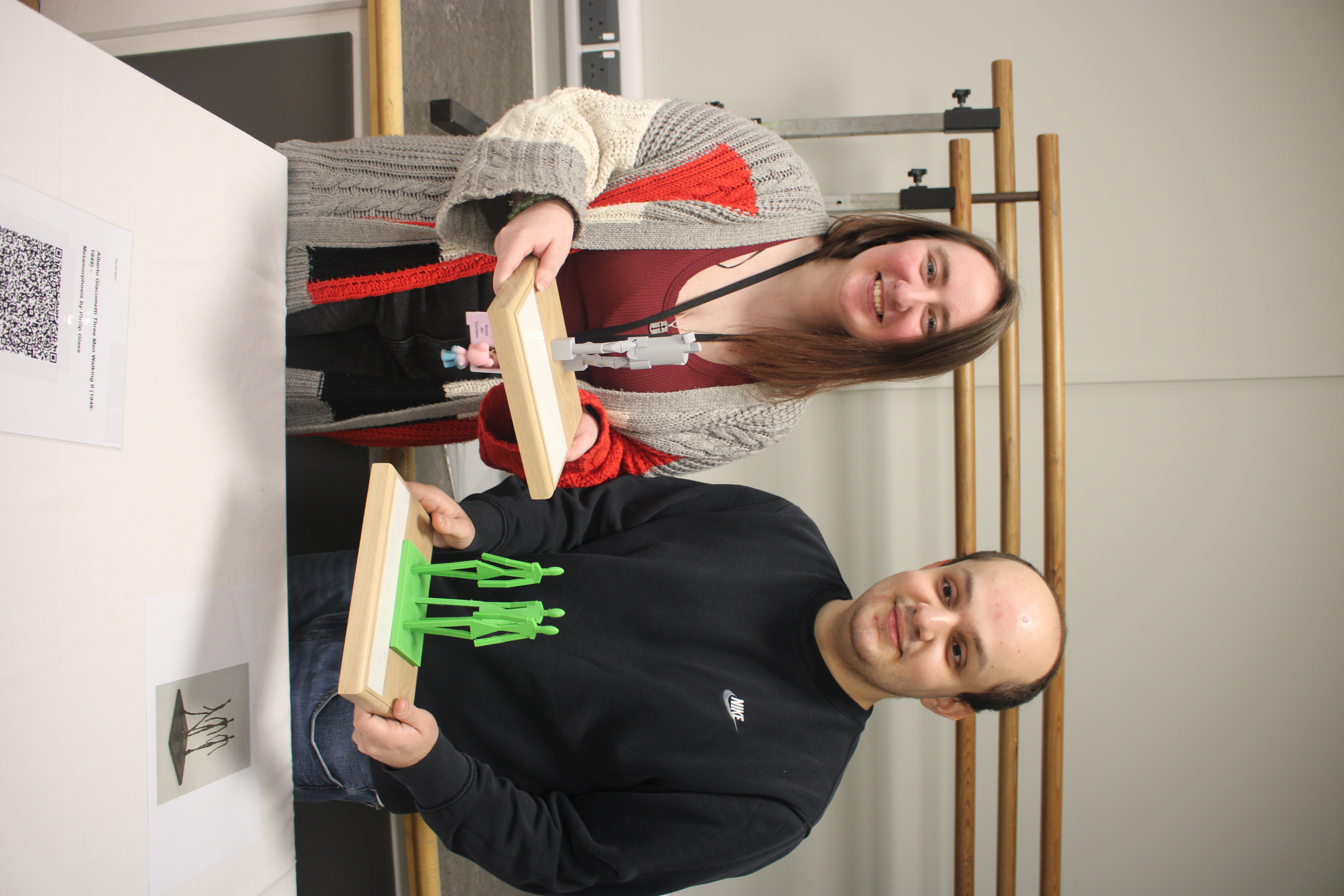 Brooke (left) and Davide (right) hold up two plinths displaying the 3D models of two of the artworks