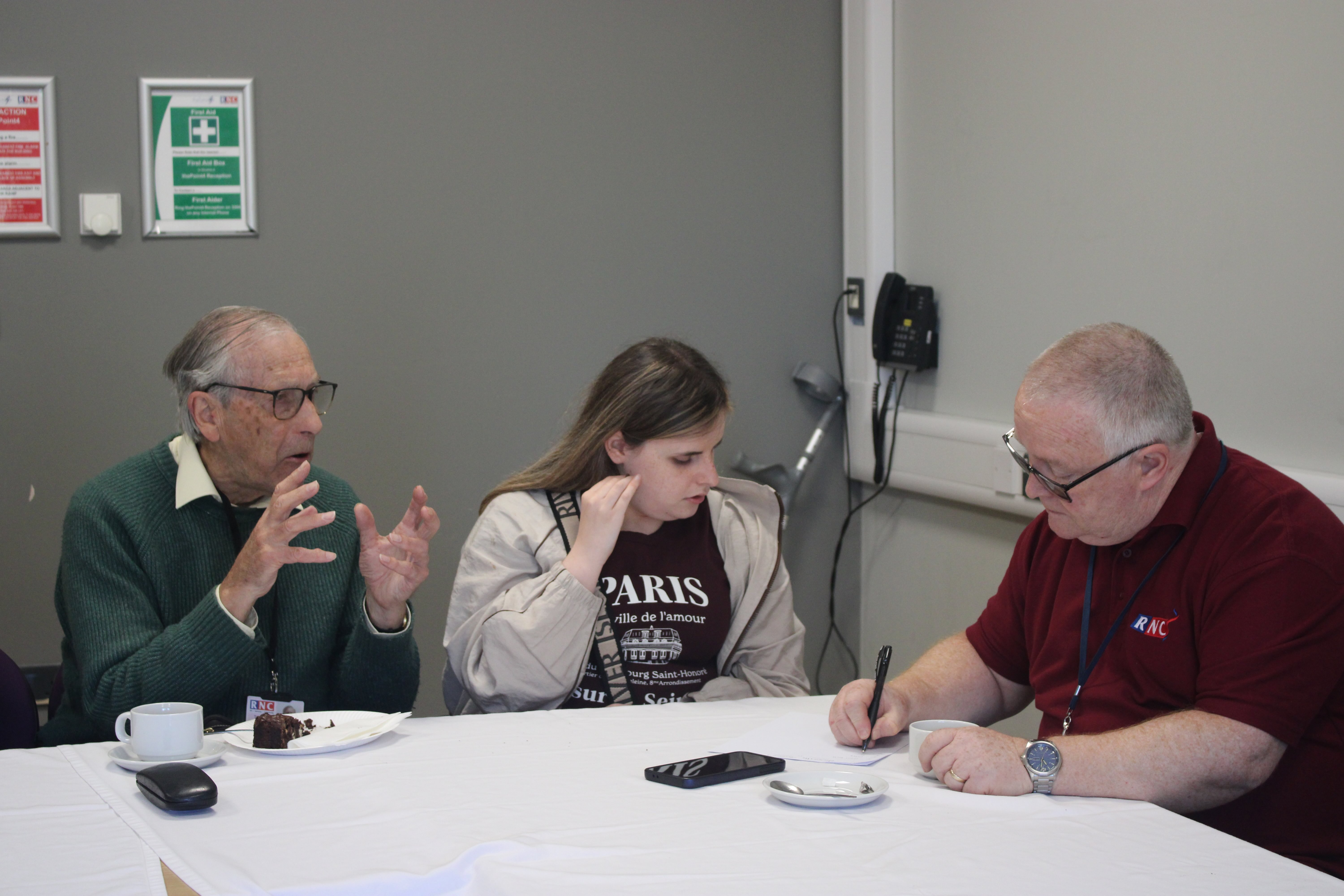 a team comprising two male volunteers and a female student sitting at a table