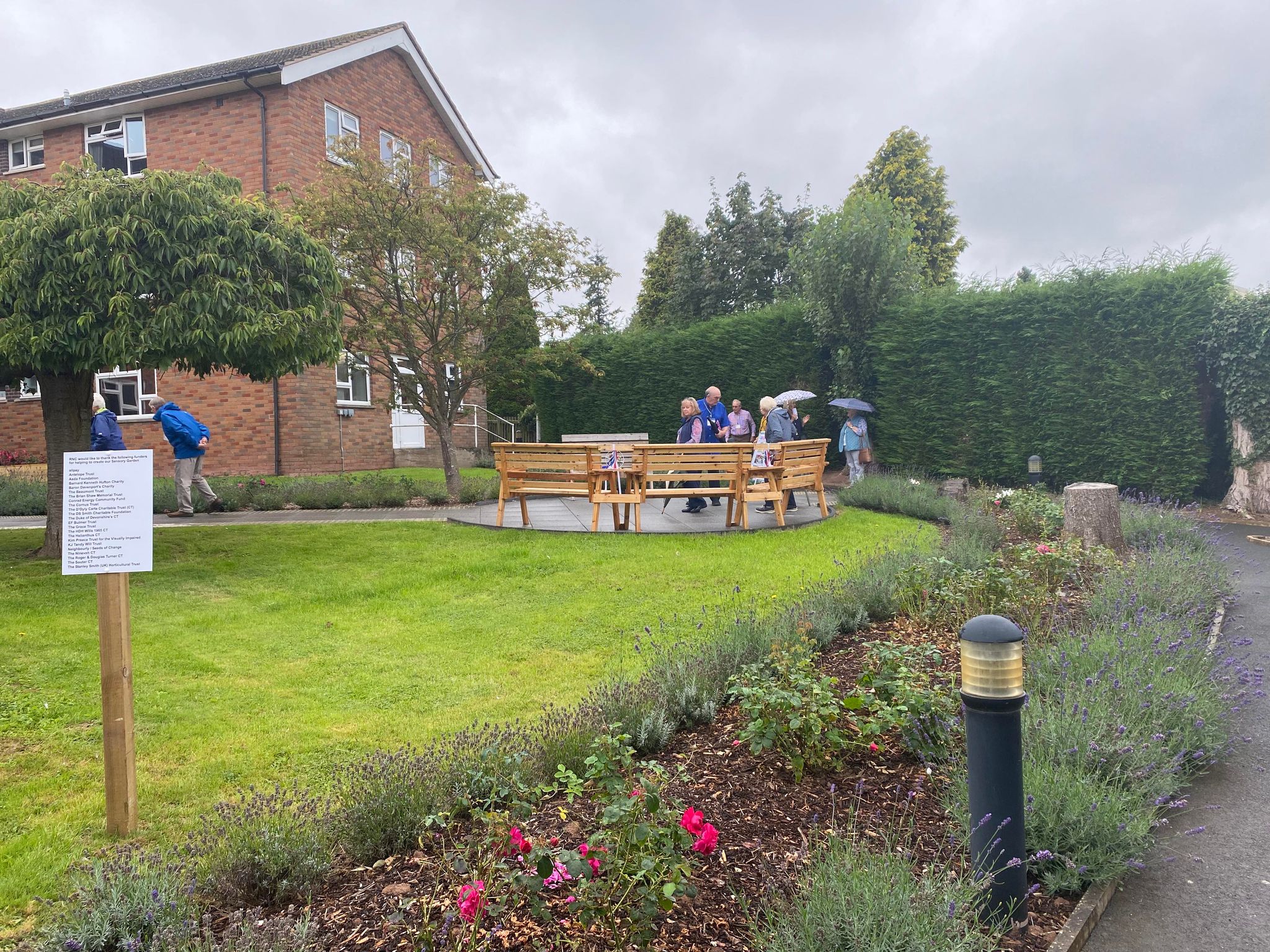 The visitors exploring the garden, some holding up umbrellas in the wet weather