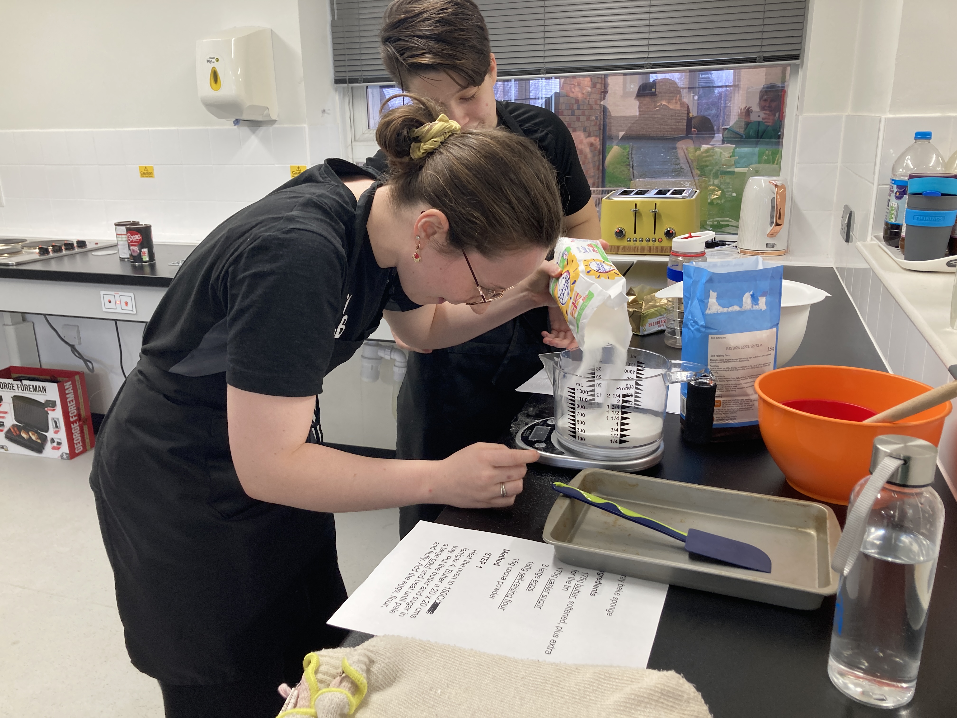 two team members weighing out sugar on the talking scales