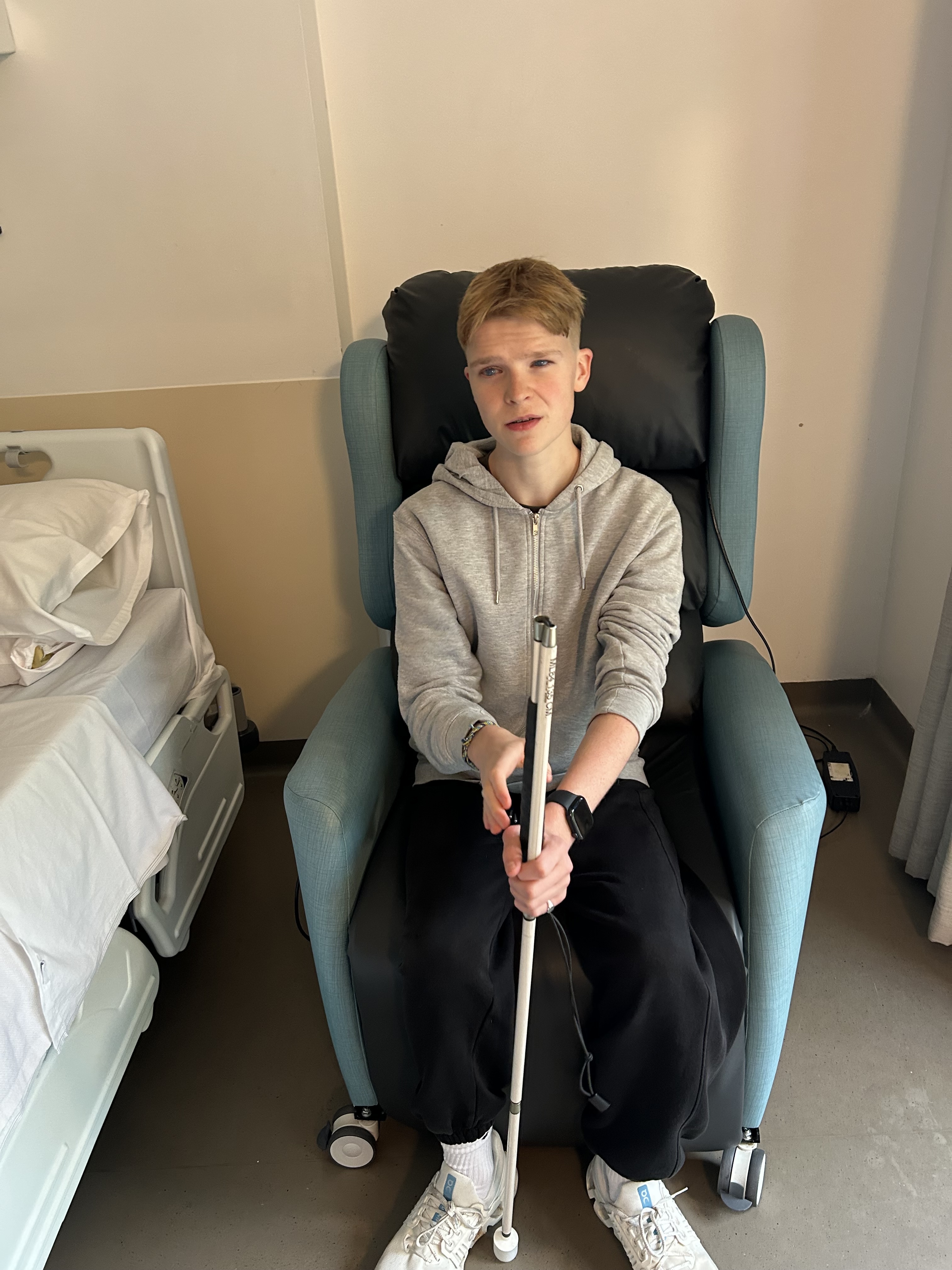 a male student sitting in a chair holding his cane