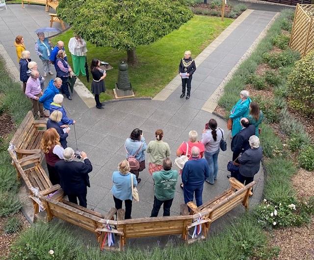 The mayor formally opens the sensory garden with invited guests surrounding her to listen to her speech