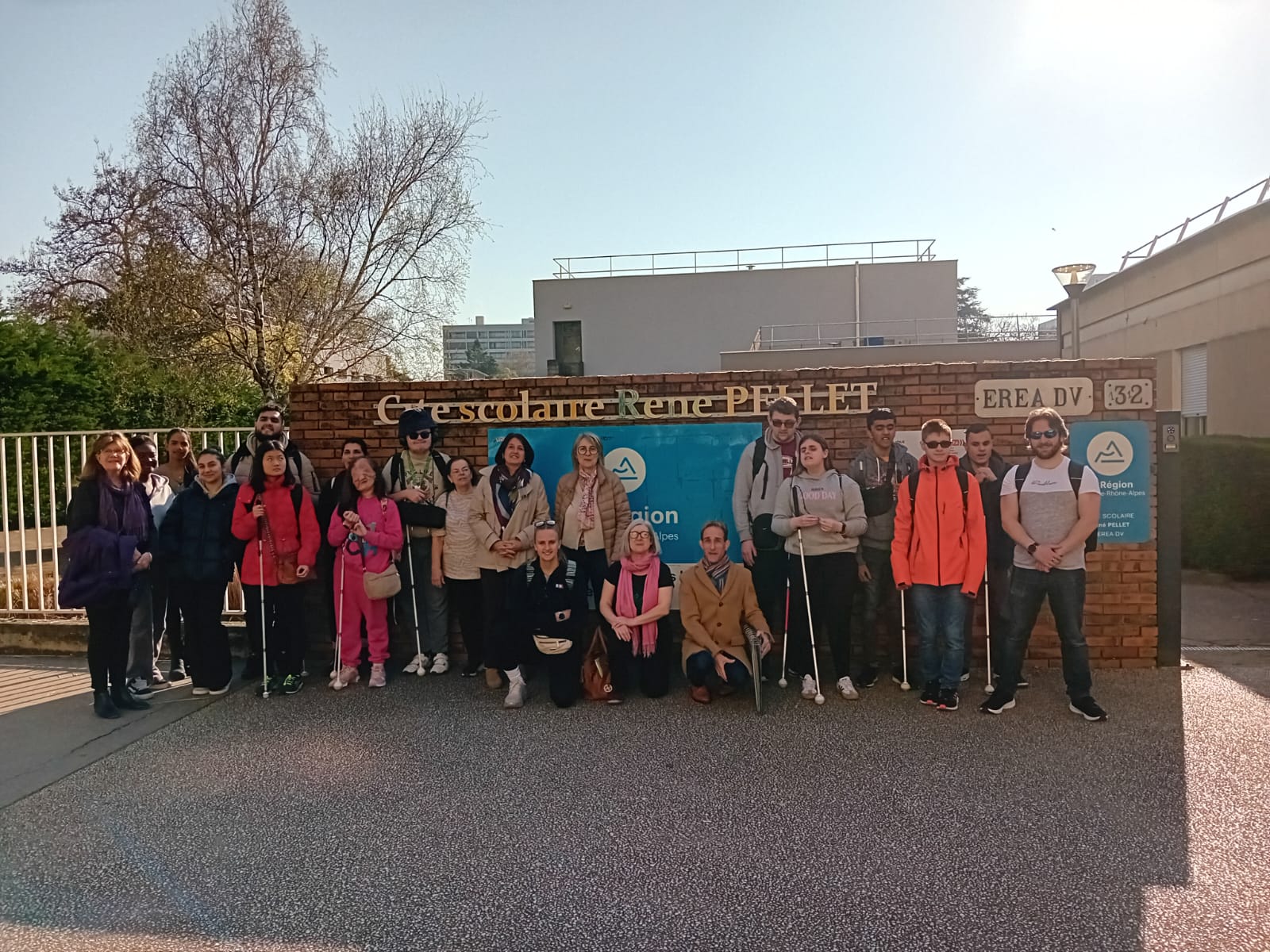The group standing in front of the school sign at the school's entrance
