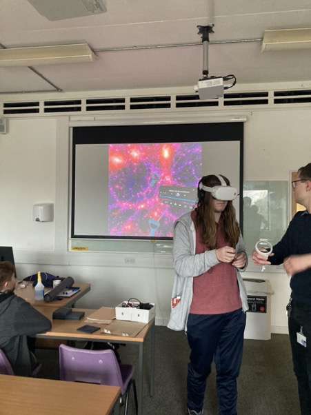 A student wearing the VR goggles and being shown how to use the equipment