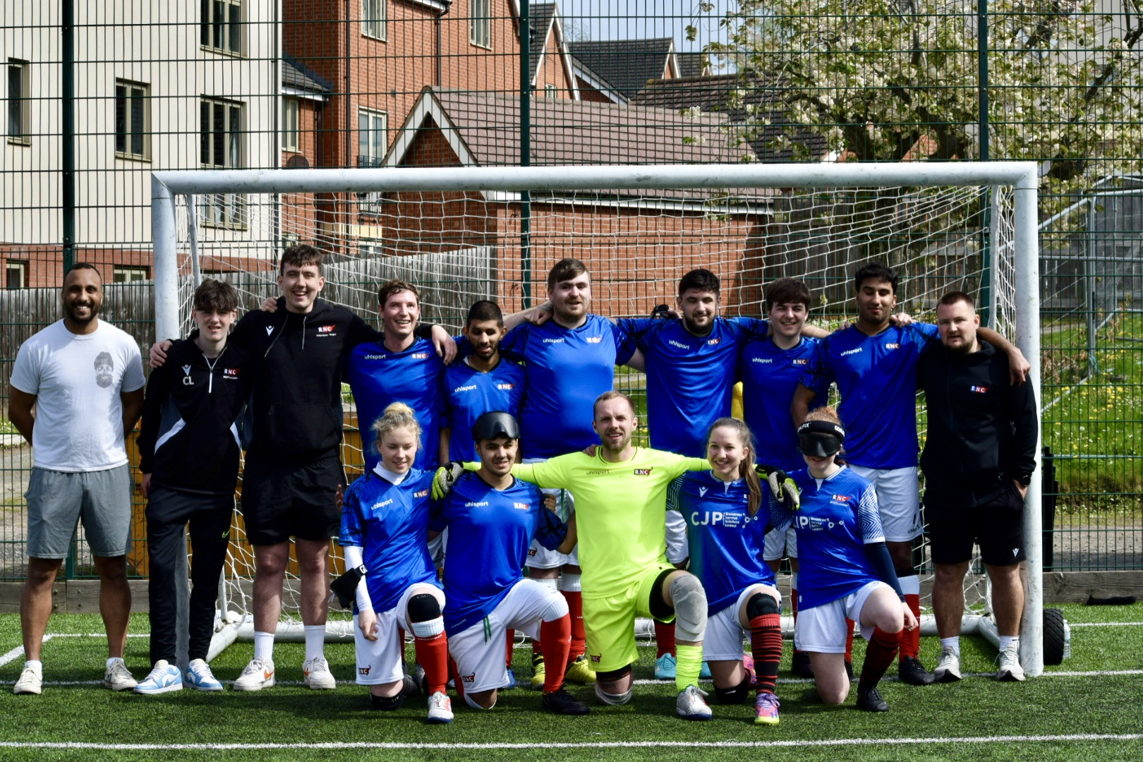 the players and coaches in the goal smiling following their victory