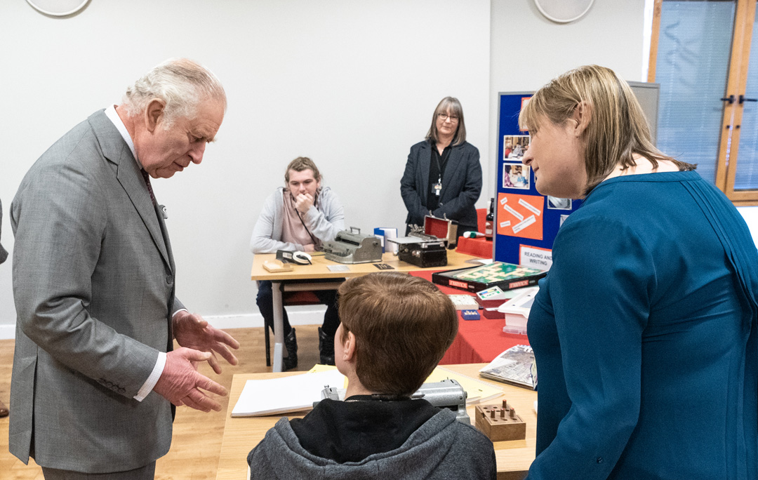 The King deep in conversation with a student about Braille