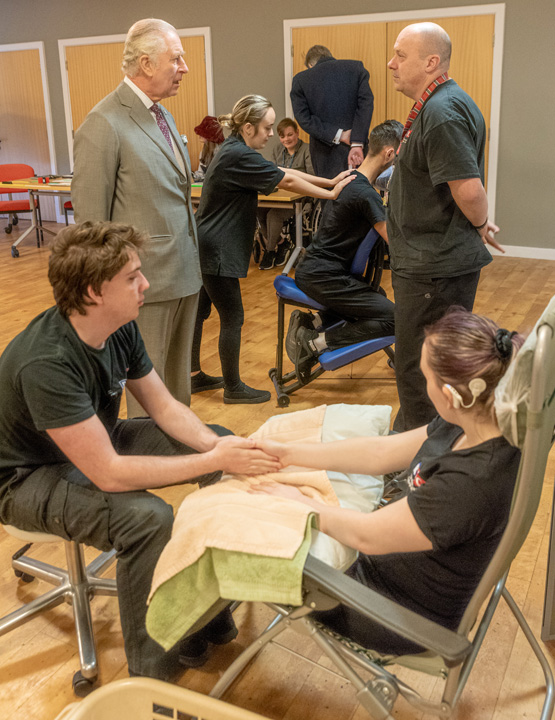 The King observes the students chair and hand massage and talks to the tutor