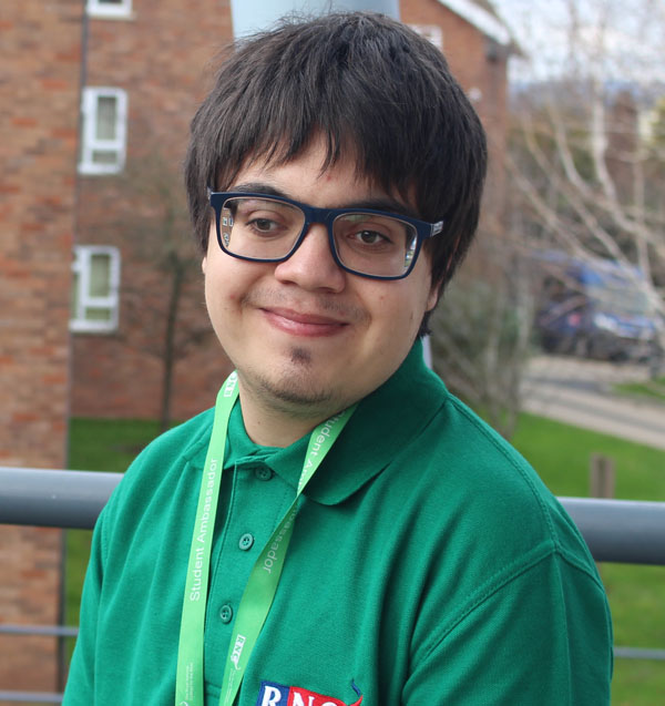 A portrait of Dom wearing his green student ambassador shirt