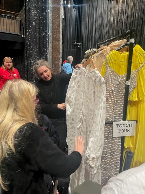 a student being shown one of the costumes, she touches the delicate fabric